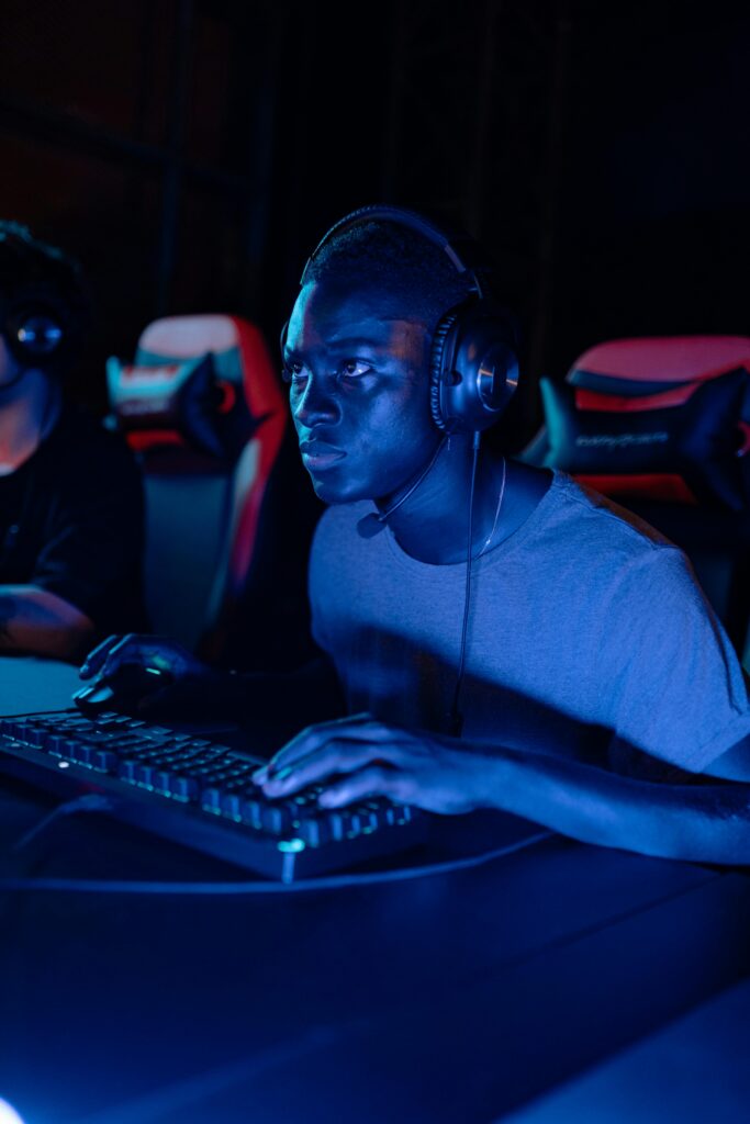 A focused gamer wearing a headset at a computer gaming station at night.