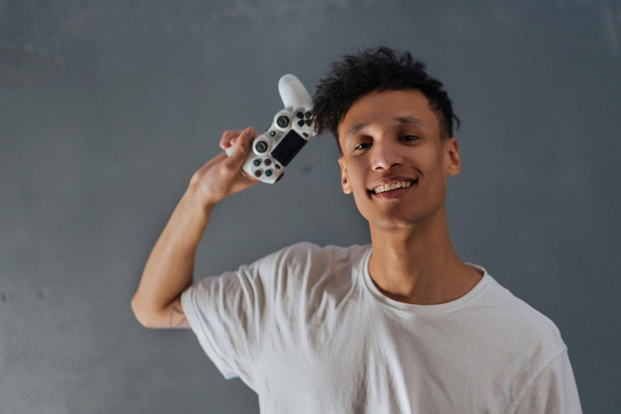 A young man with a bright smile and bandana enjoys video gaming indoors, creating a lively and fun atmosphere.